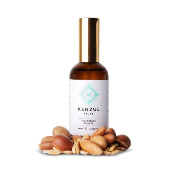 Kenzul Atlas Argan Oil 100ml amber glass bottle with gold pump cap beside argan nuts