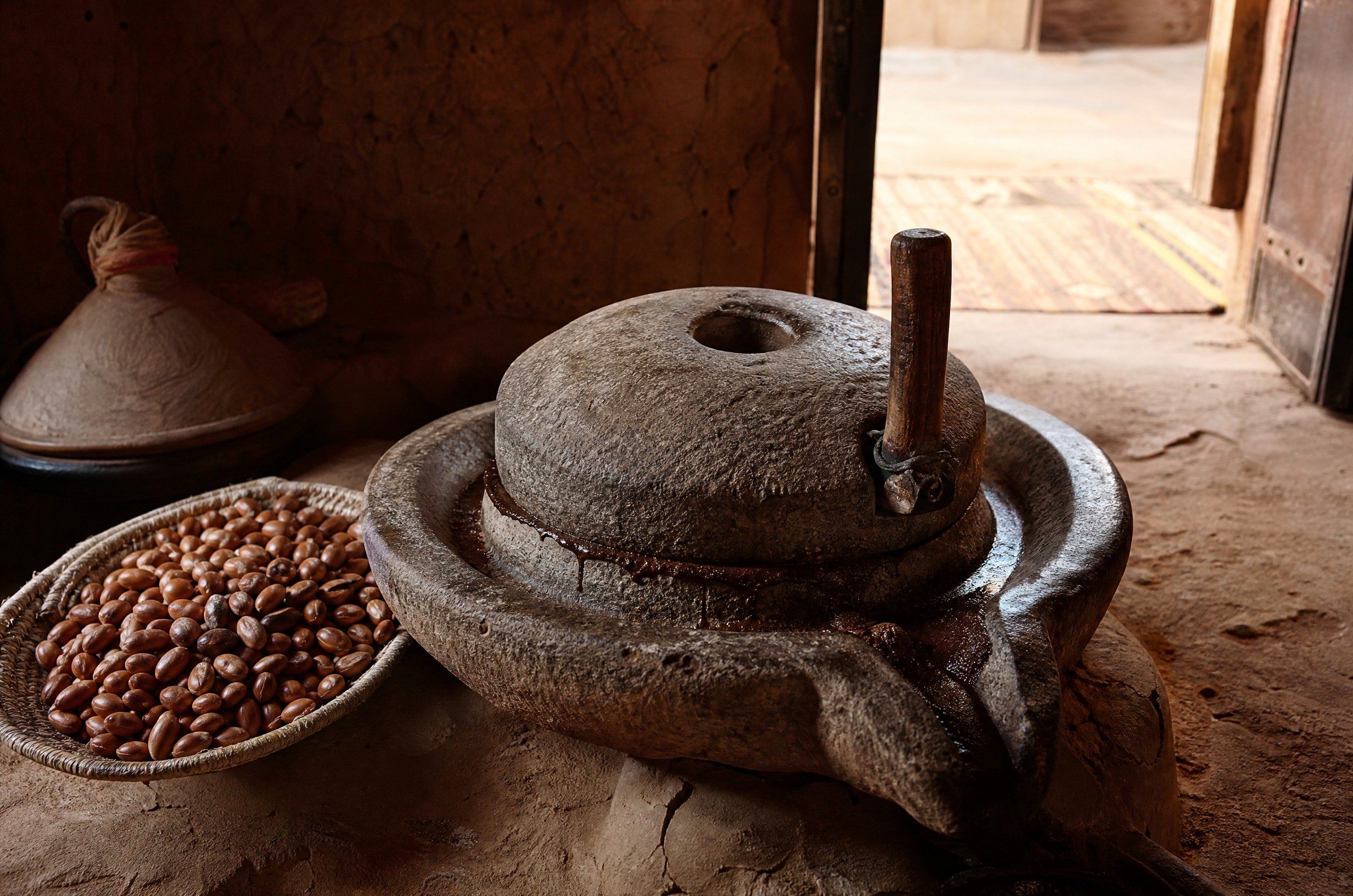 A traditional stone hand mill beside argan kernels